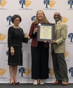 Three people standing and holding a certificate.