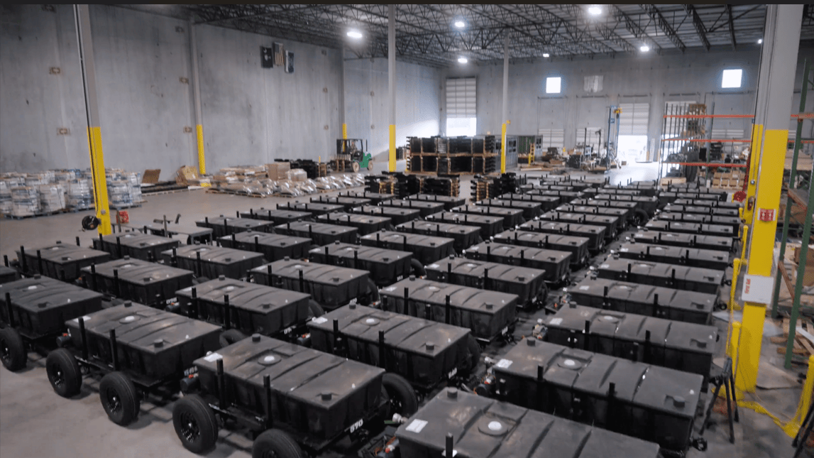 A large warehouse interior filled with rows of black industrial equipment carts on wheels.