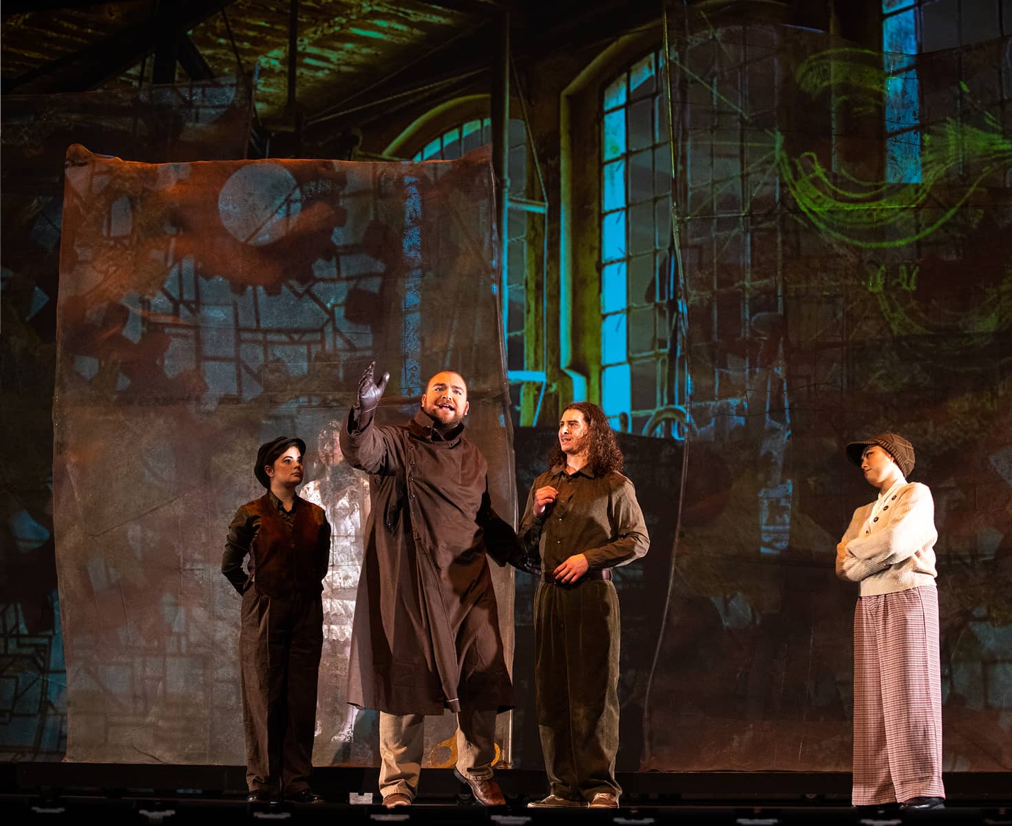 Four actors in period costumes perform onstage against a backdrop of stained glass windows.