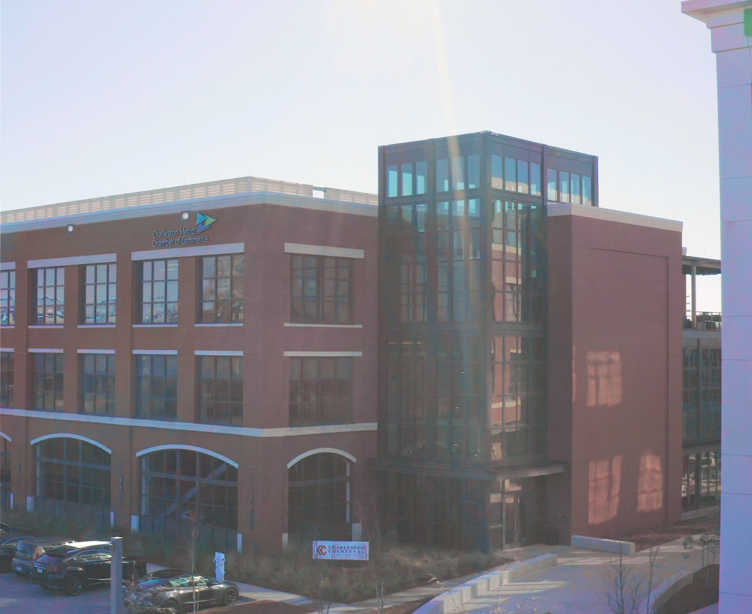 A modern red-brick office building with large windows and a glass tower. Sunlight creates a warm glow, reflecting a calm, professional environment.