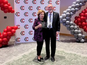A man and woman standing holding an award.