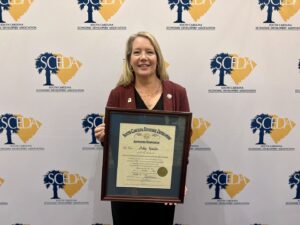 A woman standing and holding a certificate.