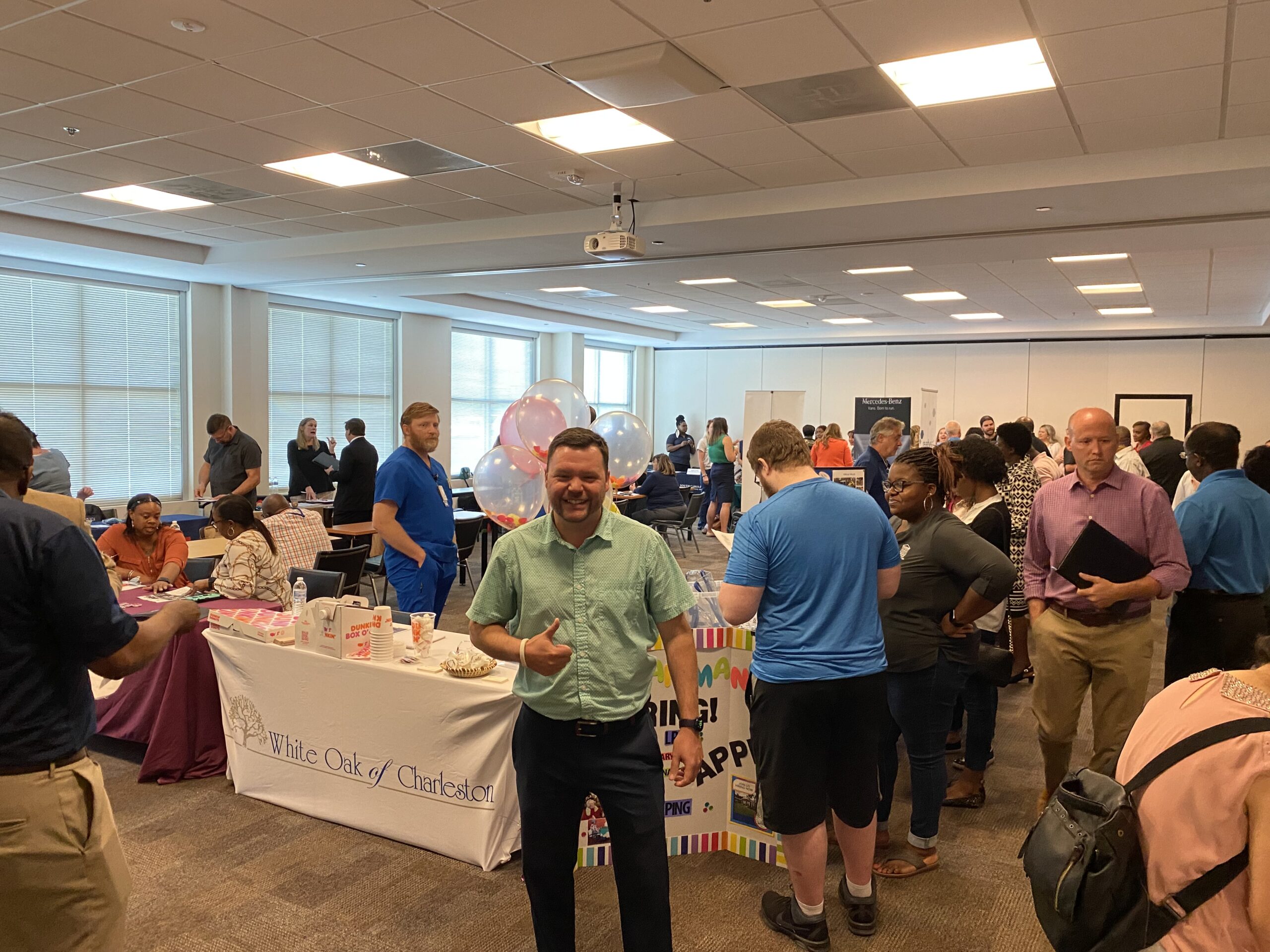 People networking and visiting employer tables at an indoor career fair.