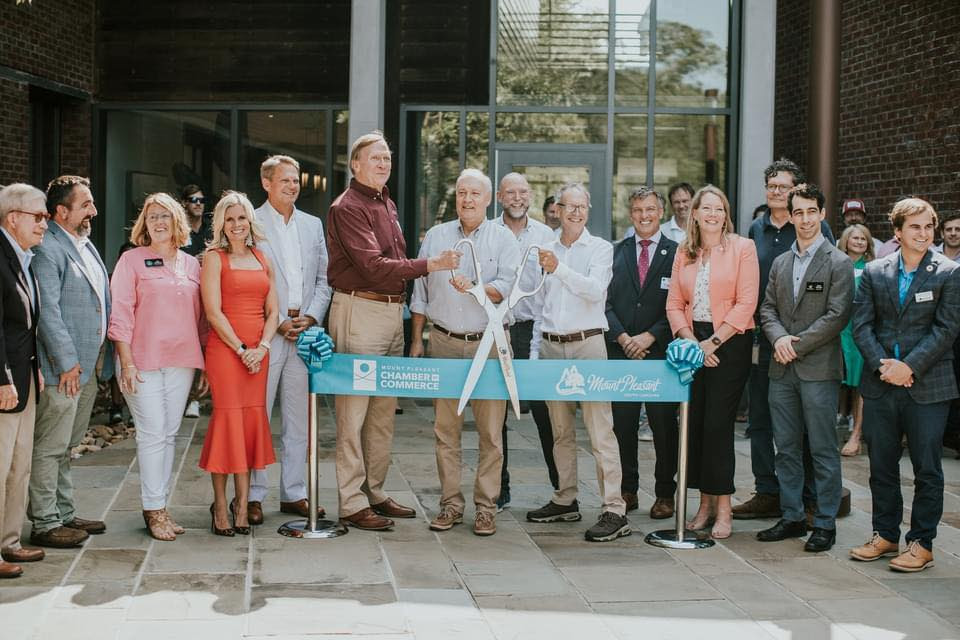 Group of community and business leaders at a ribbon-cutting ceremony outside a modern building